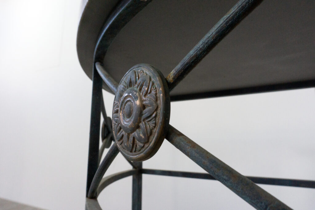 1890年代フランス製の鍛鉄コンソール。オリジナルはガラス天板ですが、紛失のため、天然石をモールテックスで包んで仕上げたビールストーン天板にカスタム。緑青がかった鍛鉄は足元がテーパー、ボールになっており丹念に制作されています。また、アール・ヌーヴォーの影響も垣間見れる花模様のブロンズパーツも魅力的です。装飾寄り