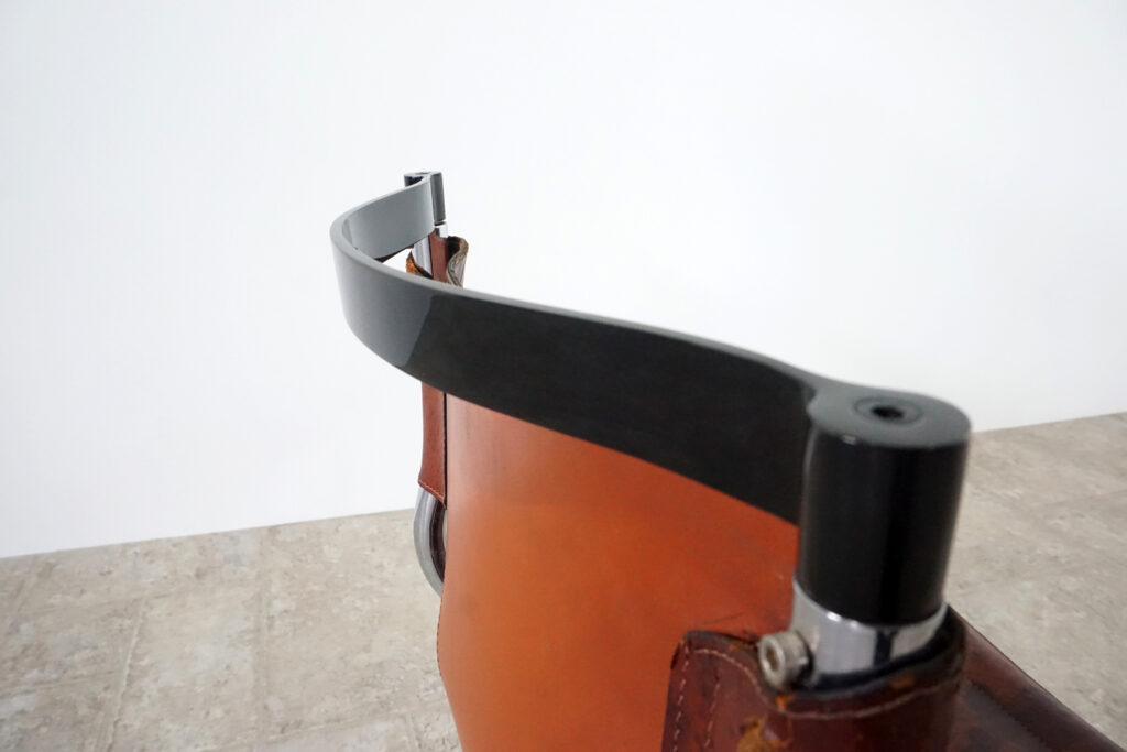 1970年代イタリア人デザイナー カルロ・バルトリ（Carlo Bartoli）によってデザインされたダイニングチェア。背もたれのアルミパーツが破損の為、より強度のあるスチール（黒クロームメッキ）を製作。深みのあるエイジングレザーと、滑らかにカーブする金属フレーム。クラシックとモダンが絶妙に交わる、スタイリッシュなダイニングチェア。背もたれ上部右後ろ