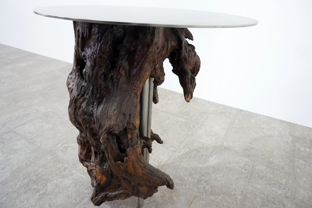 インテリアアクセントとして使われてきた流木をステンレス天板を交えてサイドテーブルへカスタム。流木の流動的で自然な風合いと、ステンレスのインダストリアルモダン感のコントラストが際立つものに仕上がりました。天板はステンレス板をランダムに荒らしたサンディング仕上げ。左寄り