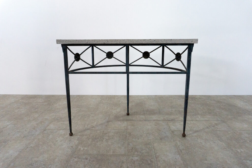 1890年代フランス製の鍛鉄コンソール。オリジナルはガラス天板ですが、紛失のため、天然石をモールテックスで包んで仕上げたビールストーン天板にカスタム。緑青がかった鍛鉄は足元がテーパー、ボールになっており丹念に制作されています。また、アール・ヌーヴォーの影響も垣間見れる花模様のブロンズパーツも魅力的です。背面