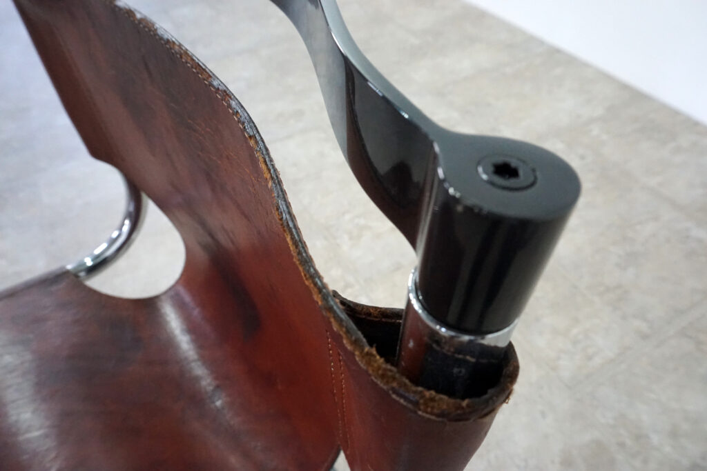 1970年代イタリア人デザイナー カルロ・バルトリ（Carlo Bartoli）によってデザインされたダイニングチェア。背もたれのアルミパーツが破損の為、より強度のあるスチール（黒クロームメッキ）を製作。深みのあるエイジングレザーと、滑らかにカーブする金属フレーム。クラシックとモダンが絶妙に交わる、スタイリッシュなダイニングチェア。背もたれ左上部