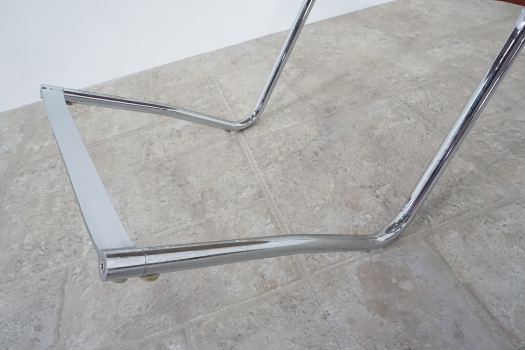 1970年代イタリア人デザイナー カルロ・バルトリ（Carlo Bartoli）によってデザインされたダイニングチェア。背もたれのアルミパーツが破損の為、より強度のあるスチール（黒クロームメッキ）を製作。深みのあるエイジングレザーと、滑らかにカーブする金属フレーム。クラシックとモダンが絶妙に交わる、スタイリッシュなダイニングチェア。足元上げ