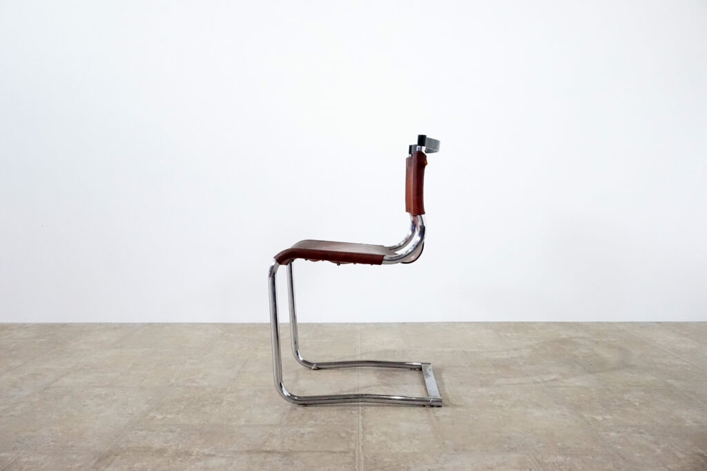 1970年代イタリア人デザイナー カルロ・バルトリ（Carlo Bartoli）によってデザインされたダイニングチェア。背もたれのアルミパーツが破損の為、より強度のあるスチール（黒クロームメッキ）を製作。深みのあるエイジングレザーと、滑らかにカーブする金属フレーム。クラシックとモダンが絶妙に交わる、スタイリッシュなダイニングチェア。左横