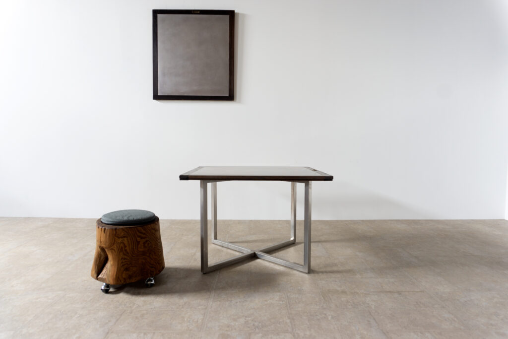 古い木製扉を再利用したテーブル。既存の木枠はそのまま活かし、中央にはステンレス板をフラットに納めています。天板は段差を抑えた構成で、実用性と意匠性を両立。脚部にはステンレス角パイプを使用し、十分な強度と安定性を確保。木部の経年変化とステンレスの均質な質感が対比され、空間に適度な緊張感を与える。一点ごとに表情の異なる木枠を使用しているため、同一仕様でも個体差があります。住宅空間から店舗什器まで幅広く使用可能。Threshold / Plane 01メイン