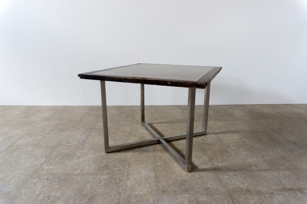 古い木製扉を再利用したテーブル。既存の木枠はそのまま活かし、中央にはステンレス板をフラットに納めています。天板は段差を抑えた構成で、実用性と意匠性を両立。脚部にはステンレス角パイプを使用し、十分な強度と安定性を確保。木部の経年変化とステンレスの均質な質感が対比され、空間に適度な緊張感を与える。一点ごとに表情の異なる木枠を使用しているため、同一仕様でも個体差があります。住宅空間から店舗什器まで幅広く使用可能。Threshold / Plane 01斜め上後方