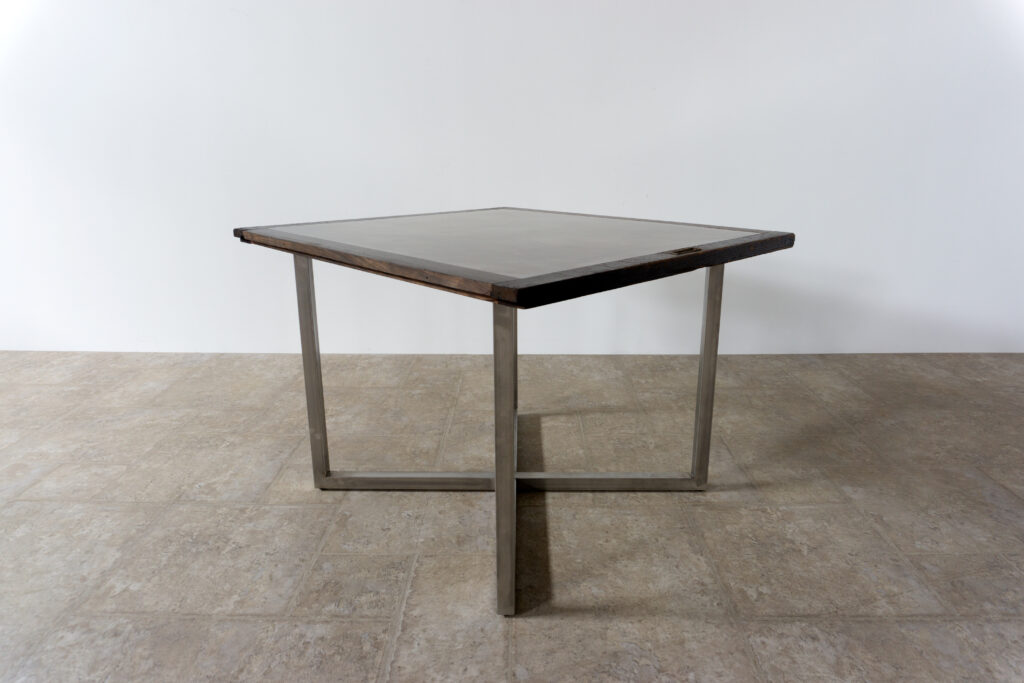 古い木製扉を再利用したテーブル。既存の木枠はそのまま活かし、中央にはステンレス板をフラットに納めています。天板は段差を抑えた構成で、実用性と意匠性を両立。脚部にはステンレス角パイプを使用し、十分な強度と安定性を確保。木部の経年変化とステンレスの均質な質感が対比され、空間に適度な緊張感を与える。一点ごとに表情の異なる木枠を使用しているため、同一仕様でも個体差があります。住宅空間から店舗什器まで幅広く使用可能。Threshold / Plane 01斜め上