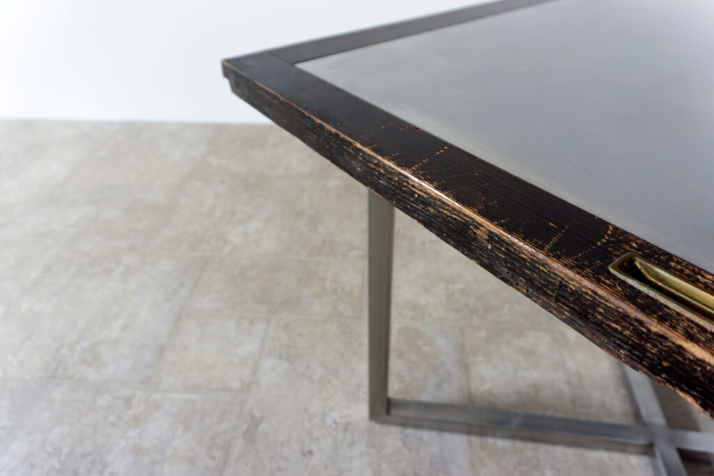 古い木製扉を再利用したテーブル。既存の木枠はそのまま活かし、中央にはステンレス板をフラットに納めています。天板は段差を抑えた構成で、実用性と意匠性を両立。脚部にはステンレス角パイプを使用し、十分な強度と安定性を確保。木部の経年変化とステンレスの均質な質感が対比され、空間に適度な緊張感を与える。一点ごとに表情の異なる木枠を使用しているため、同一仕様でも個体差があります。住宅空間から店舗什器まで幅広く使用可能。Threshold / Plane 01天板手前