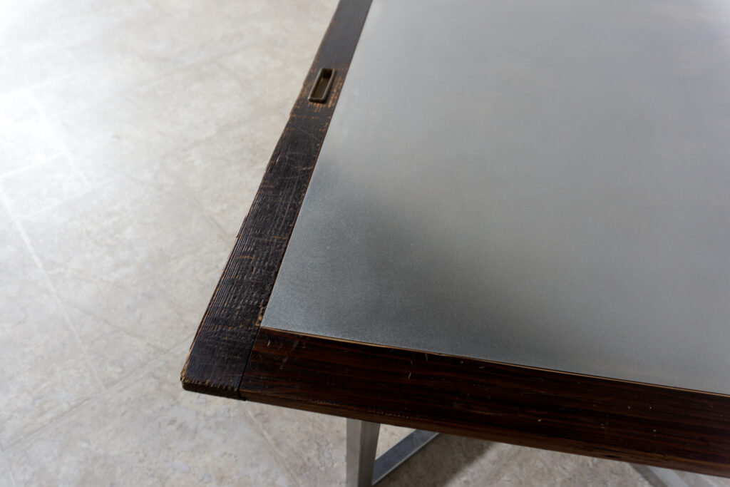 古い木製扉を再利用したテーブル。既存の木枠はそのまま活かし、中央にはステンレス板をフラットに納めています。天板は段差を抑えた構成で、実用性と意匠性を両立。脚部にはステンレス角パイプを使用し、十分な強度と安定性を確保。木部の経年変化とステンレスの均質な質感が対比され、空間に適度な緊張感を与える。一点ごとに表情の異なる木枠を使用しているため、同一仕様でも個体差があります。住宅空間から店舗什器まで幅広く使用可能。Threshold / Plane 01天板左下