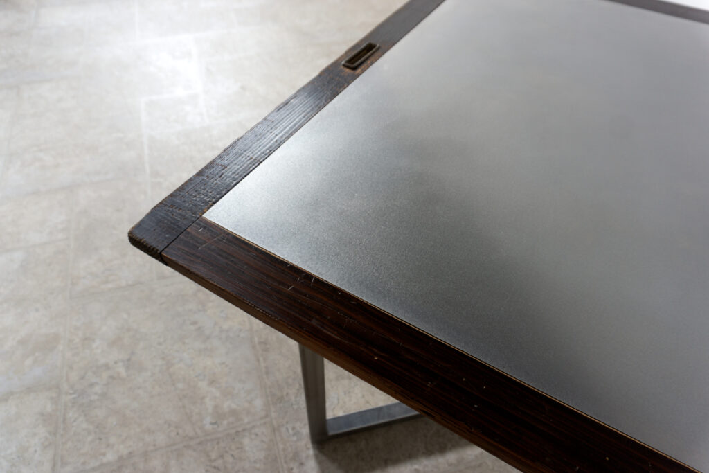 古い木製扉を再利用したテーブル。既存の木枠はそのまま活かし、中央にはステンレス板をフラットに納めています。天板は段差を抑えた構成で、実用性と意匠性を両立。脚部にはステンレス角パイプを使用し、十分な強度と安定性を確保。木部の経年変化とステンレスの均質な質感が対比され、空間に適度な緊張感を与える。一点ごとに表情の異なる木枠を使用しているため、同一仕様でも個体差があります。住宅空間から店舗什器まで幅広く使用可能。Threshold / Plane 01角1
