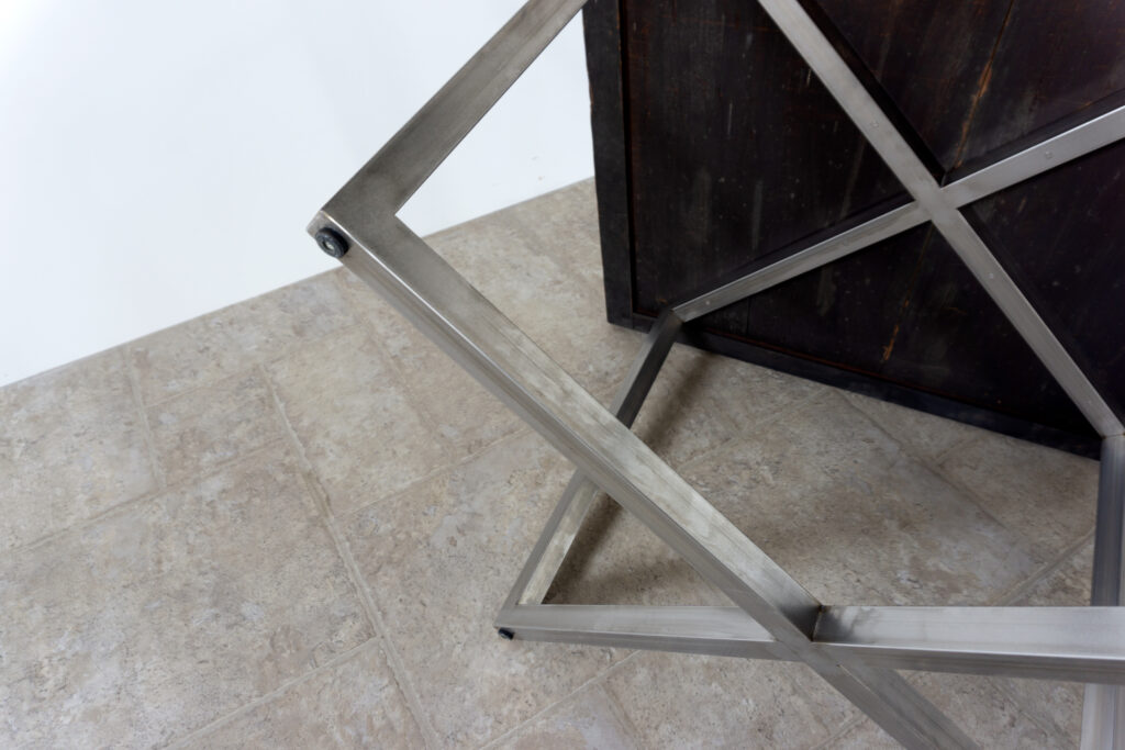 古い木製扉を再利用したテーブル。既存の木枠はそのまま活かし、中央にはステンレス板をフラットに納めています。天板は段差を抑えた構成で、実用性と意匠性を両立。脚部にはステンレス角パイプを使用し、十分な強度と安定性を確保。木部の経年変化とステンレスの均質な質感が対比され、空間に適度な緊張感を与える。一点ごとに表情の異なる木枠を使用しているため、同一仕様でも個体差があります。住宅空間から店舗什器まで幅広く使用可能。Threshold / Plane 01足寄り